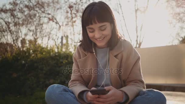 Mulher bonita usa smartphone no parque — Vídeo de Stock