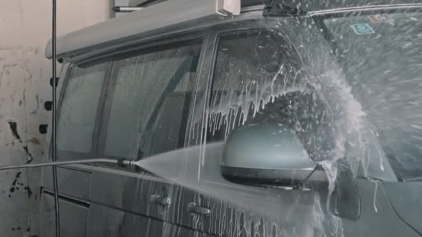 Чоловік чистить великий фургон або автомобіль на мийці самообслуговування — стокове відео