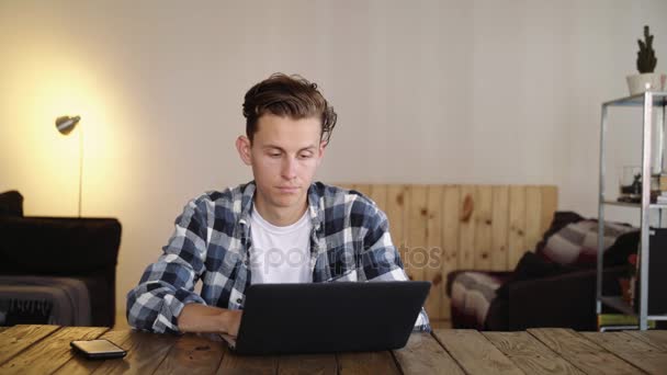 Zły człowiek sfrustrowany rozbija laptopa na stole — Wideo stockowe