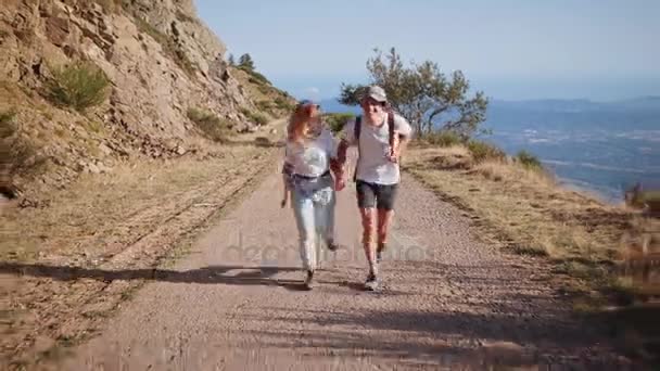 Young hipster couple hikes on mountain road on sunset — Stock Video