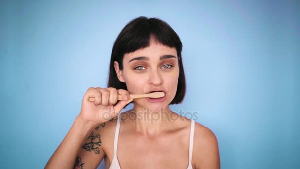Zahnbürste und attraktive Brünette auf farbigen Hintergründen — Stockvideo