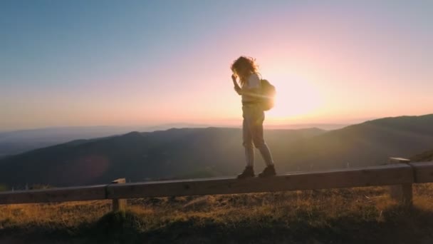 Vrouw wandelingen op de berg doorgeven zonsondergang — Stockvideo