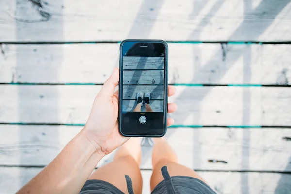 Frau macht Foto auf Smartphone von Turnschuh — Stockfoto