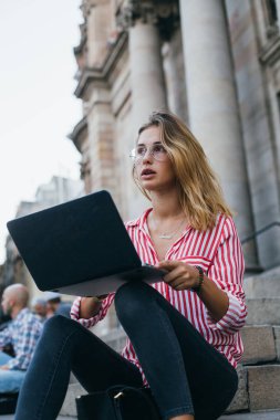 Çekici kadın öğrenci dizüstü bilgisayar ile merdivenlerde oturur