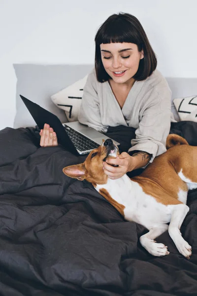 Woman and dog work from home bed