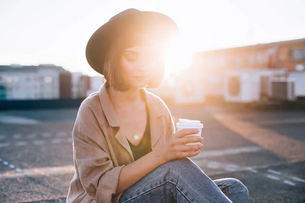Modelo de moda sostiene taza de café en la puesta del sol — Foto de Stock
