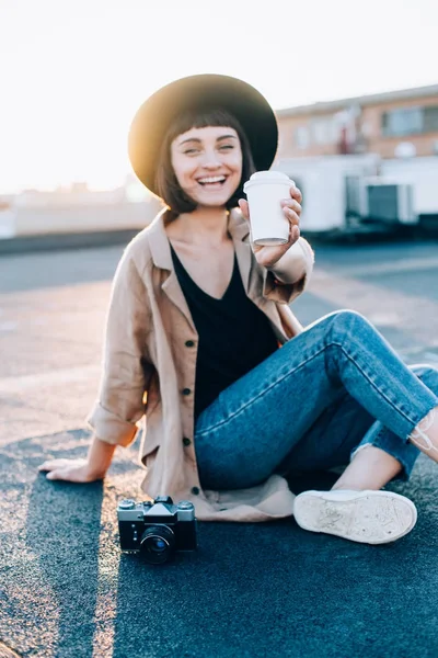 Kadın kahve fincanı günbatımı üzerinde tutar.