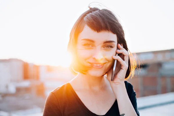 Kaunis nainen puhuu älypuhelimella auringonlaskussa — kuvapankkivalokuva