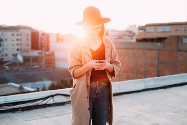 Nainen käyttää älypuhelinta auringonlaskun aikana — kuvapankkivalokuva