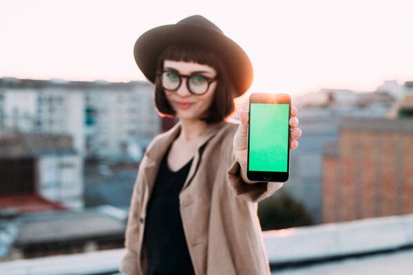 Красивая хипстерша показывает смартфон
