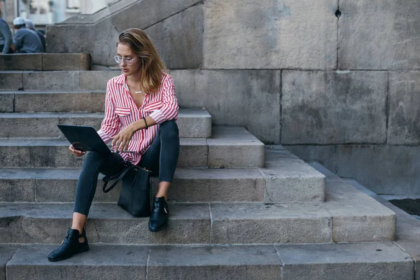 Frau sitzt mit Laptop auf Stufen der Universität — Stockfoto