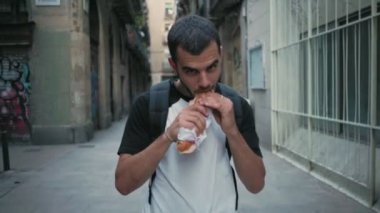 Aç öğrenci sandviç yolda yiyor.