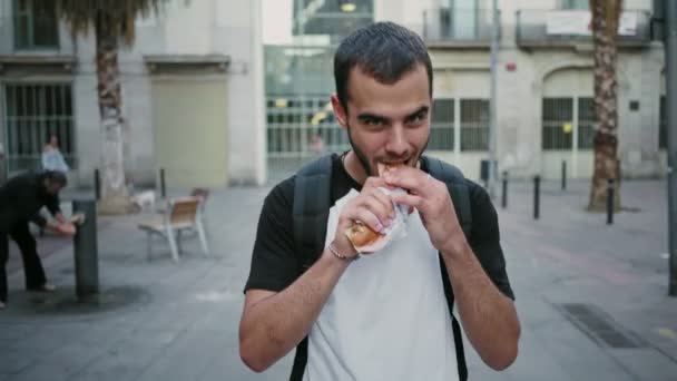 Aç öğrenci sandviç yolda yiyor. — Stok video