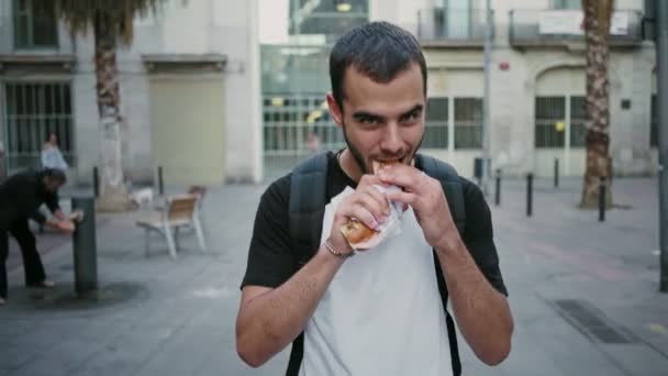 Studente affamato mangia panino sulla sua strada — Video Stock