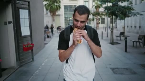 Głodny student zjada kanapkę w drodze — Wideo stockowe