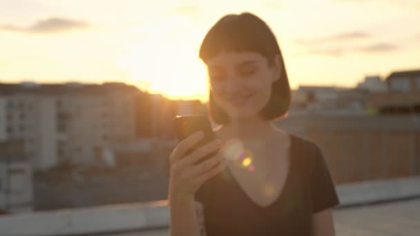 Atractiva morena con gadget en la azotea al atardecer — Vídeos de Stock