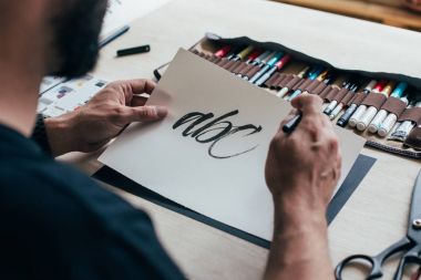 kağıt kalem çantası ile birlikte masada çizim üzerinde el yazısı harfler Hat sanatı öğrenme adam