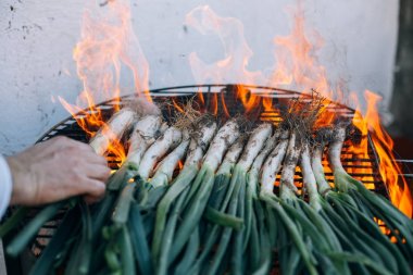 Taze soğan ve calcots, geleneksel İspanyolca, Katalanca, Meksika yemeği ızgarada Barbekü yapma adam