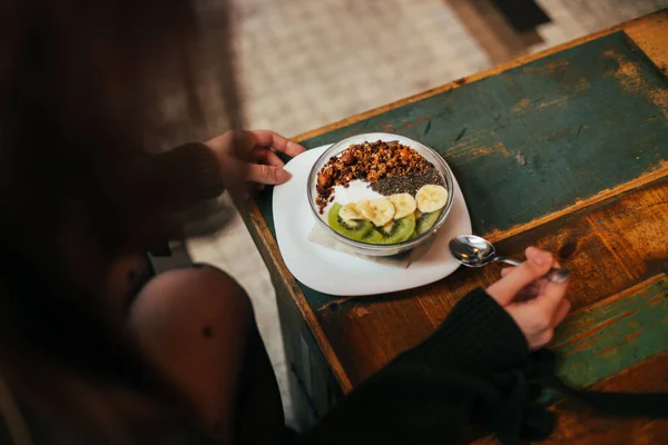 person eating morning breakfast with fruits in bowl, granola with fruits