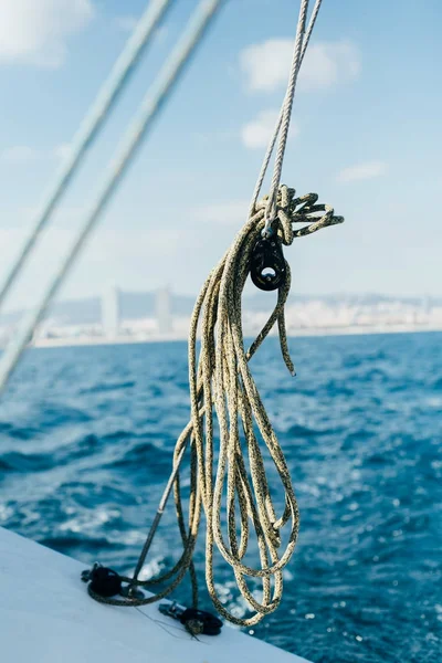 Green nautical rope inside pulley on sailboat or yacht, on sunny summer day