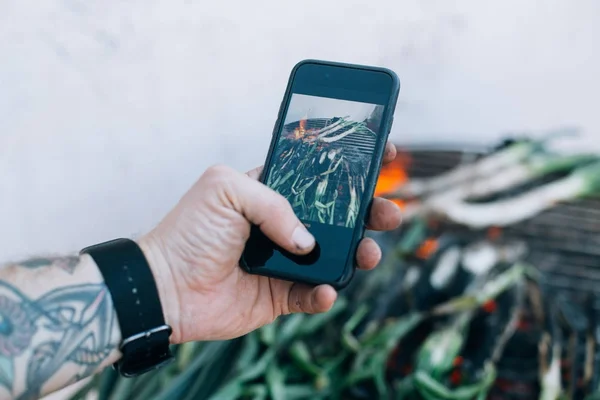 Homem Cozinhando Churrasco Grelha Cebolinhas Calcotes Faz Fotos Alimentos Smartphone — Fotografia de Stock