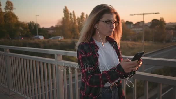 Szép tini lány használja a smartphone a naplemente — Stock videók