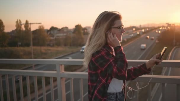 Szép tini lány használja a smartphone a naplemente — Stock videók