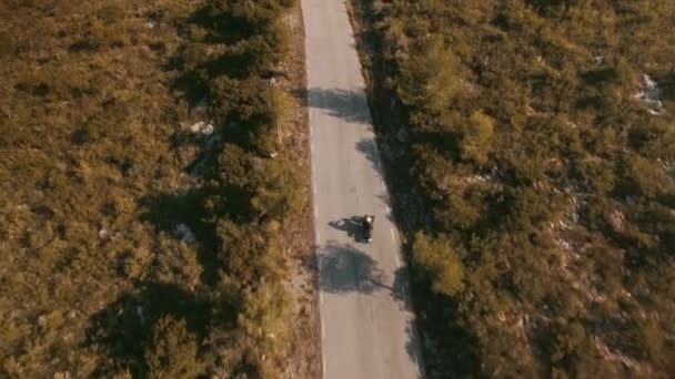 Drohnenaufnahmen über einsamen Reisenden, der mit seinem Motorrad auf epischen Bergstraßen unterwegs ist — Stockvideo