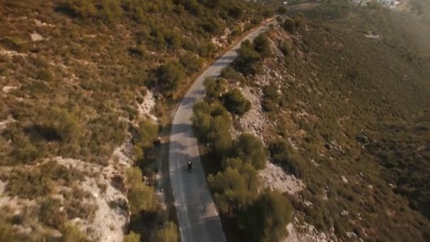 壮大な風景の山の道路で彼のバイクに乗って孤独な旅人にドローン映像 — ストック動画