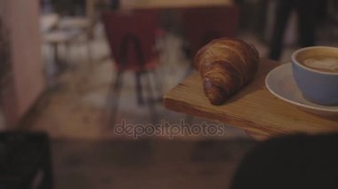 Garson kahve ve kruvasan tabloya café'de taşır