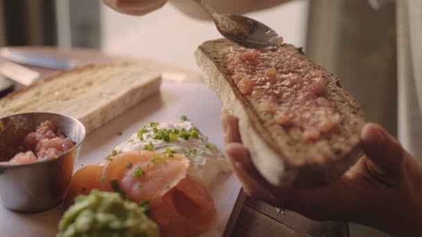 Женщина разбрасывает помидоры по хлебным тостам — стоковое видео
