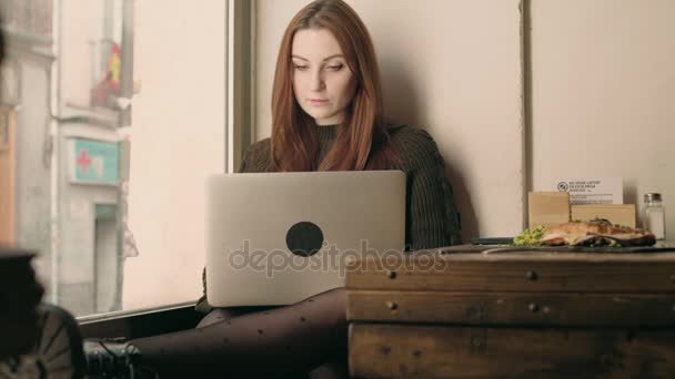 Jonge vrouw student werkt op afstand bij café — Stockvideo