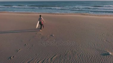 Sörfçü okyanus deniz kıyısında yanında yürüyor