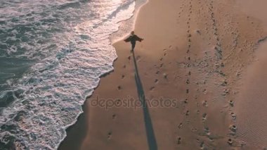 Telefon ile mutlu kız okyanus yanındaki sahil yürür