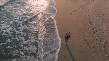 Telefon ile mutlu kız okyanus yanındaki sahil yürür