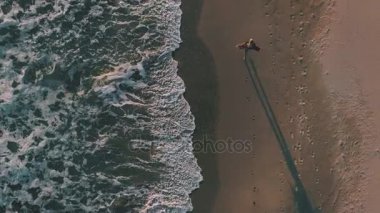 Telefon ile mutlu kız okyanus yanındaki sahil yürür