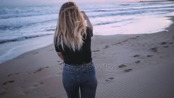 Menina loira feliz na praia ao pôr do sol ou crepúsculo — Vídeo de Stock