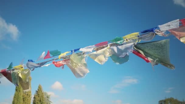 Buddhism religion, many flags hanging in air next to monastery — Stock Video