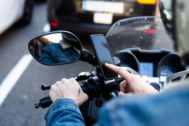 Motosiklet sürücüsü bisiklet üzerinde sabit smartphone kullanarak görünümünü kırpılmış