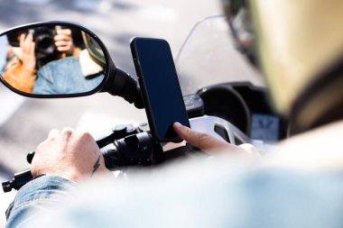 Motosiklet sürücüsü bisiklet üzerinde sabit smartphone kullanarak görünümünü kırpılmış