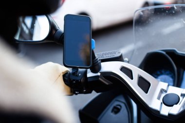 Motosiklet sürücüsü bisiklet üzerinde sabit smartphone kullanarak görünümünü kırpılmış