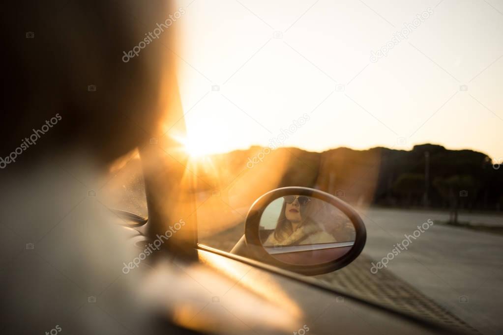 cropped view of woman reflected in sideview mirror of convertible cabriolet car