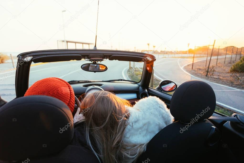 cropped rear portrait of woman and man in cabriolet convertible car with open roof