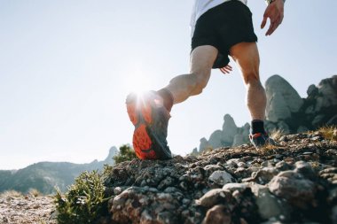 Spor ayakkabı ayakkabı sole ultra trail maraton yarış sırasında dağ yolu üzerinde sert kayalık arazide çalışan alt. Güçlü sağlıklı atletik erkek, eğitimli bacaklar açık havada egzersiz sırasında uygun.
