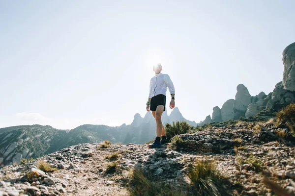 在远足或徒步旅行期间 适合和有吸引力的人站在岩石或山崖的顶端 穿着专业的运动服或装备 看着相机 在超径跑后自信十足 — 图库照片