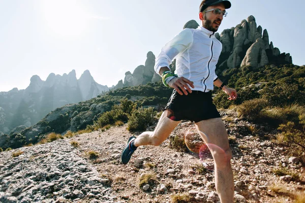 Fast and strong, fit athletic man runs on mountain path or trail during ultra marathon race, hard training workout, healthy lifestyle choice to spend time outdoors in nature in national park