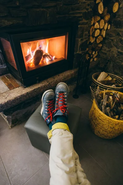リビング ルームや山スキーのホテルのロビーで燃えて 温かく居心地の良いホット暖炉の前で重労働の革冬のブーツで彼の足を休んで男の上からハメ撮り写真 — ストック写真