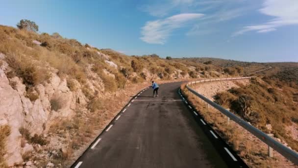 Hipster man monte sur skateboard sur route de montagne — Video