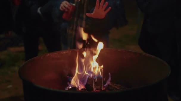 Люди теплые руки рядом с огнем на улице — стоковое видео
