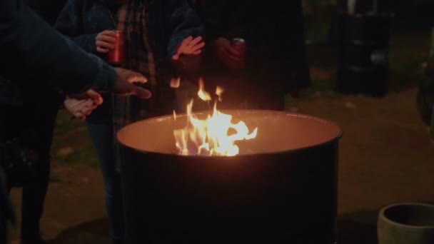 Люди зігрівають руки біля вогню на вулиці — стокове відео